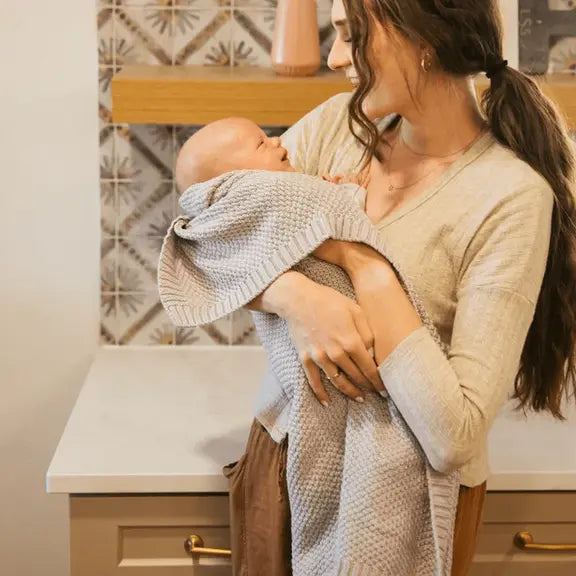 Woman holding a baby wrapped in a towel in a kitchen setting