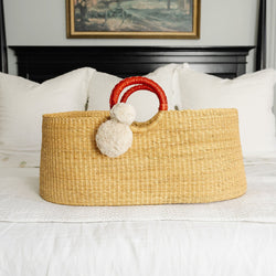 Woven basket with decorative handles on a bed