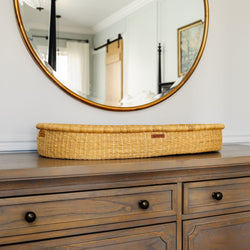 Wooden dresser with round mirror and woven basket on top